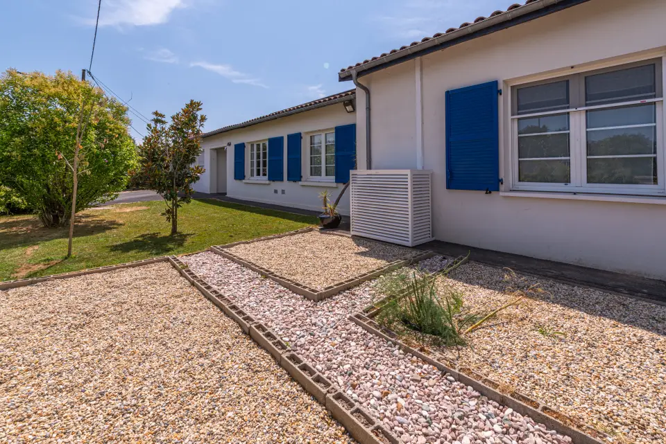 La villa vue depuis la rue, volets bleus et allée de graviers