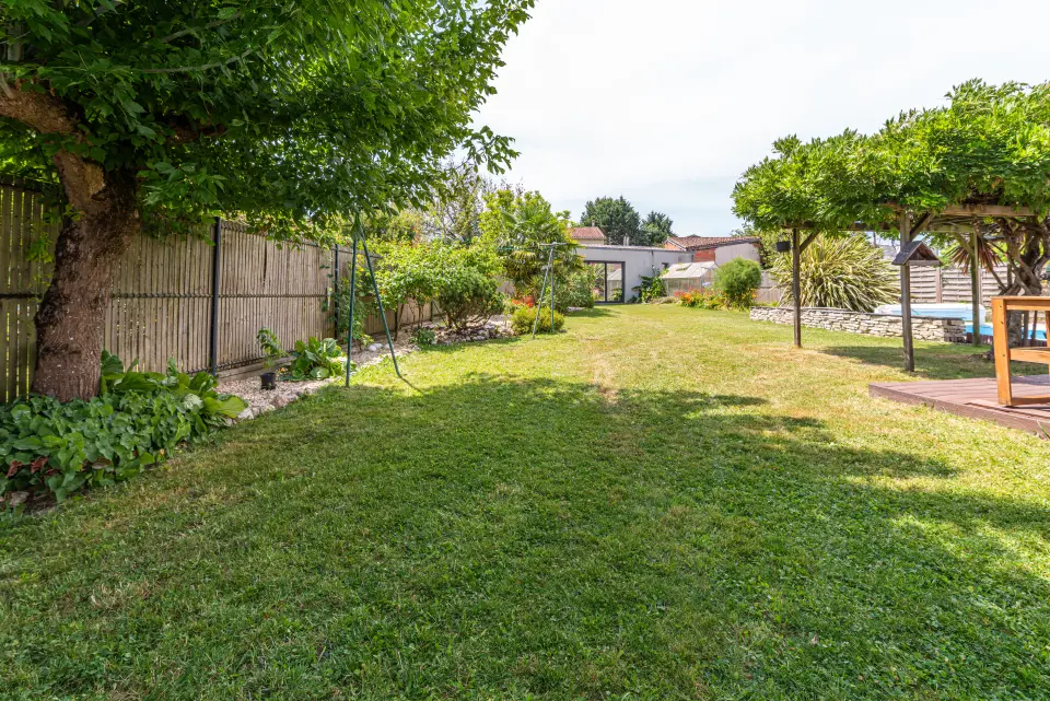 Le grand jardin : pelouse, arbres d’ombre et la piscine au fond